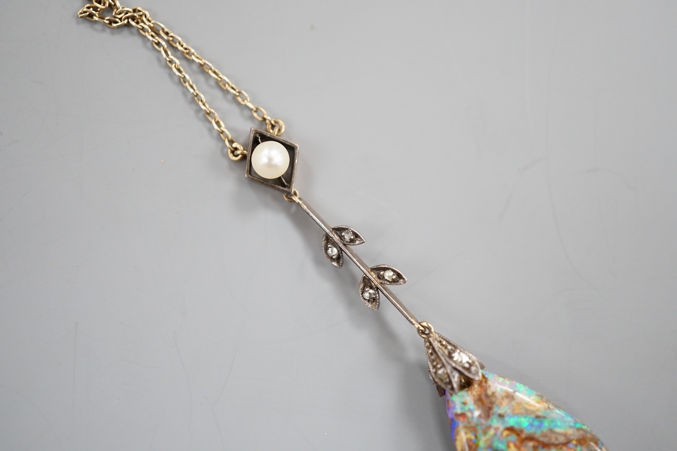 An early 20th century yellow and white metal, pear shaped black opal, rose cut diamond and seed pearl set drop pendant necklace, pendant overall 57mm, chain stamped 9ct, 37cm, gross weight 5.9 grams.